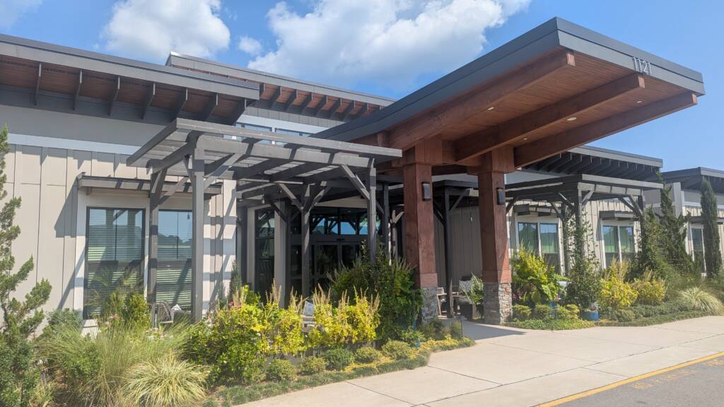 Calyx Senior Living Exterior Entrance with lots of greenery and clouds on a beauitful day