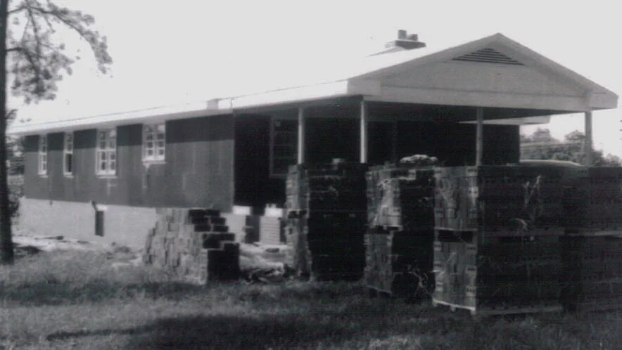 The unfinished parsonage exterior with brick stacks beside the building.