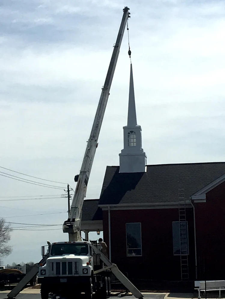 The new church steeple being lifted into place by a crane.