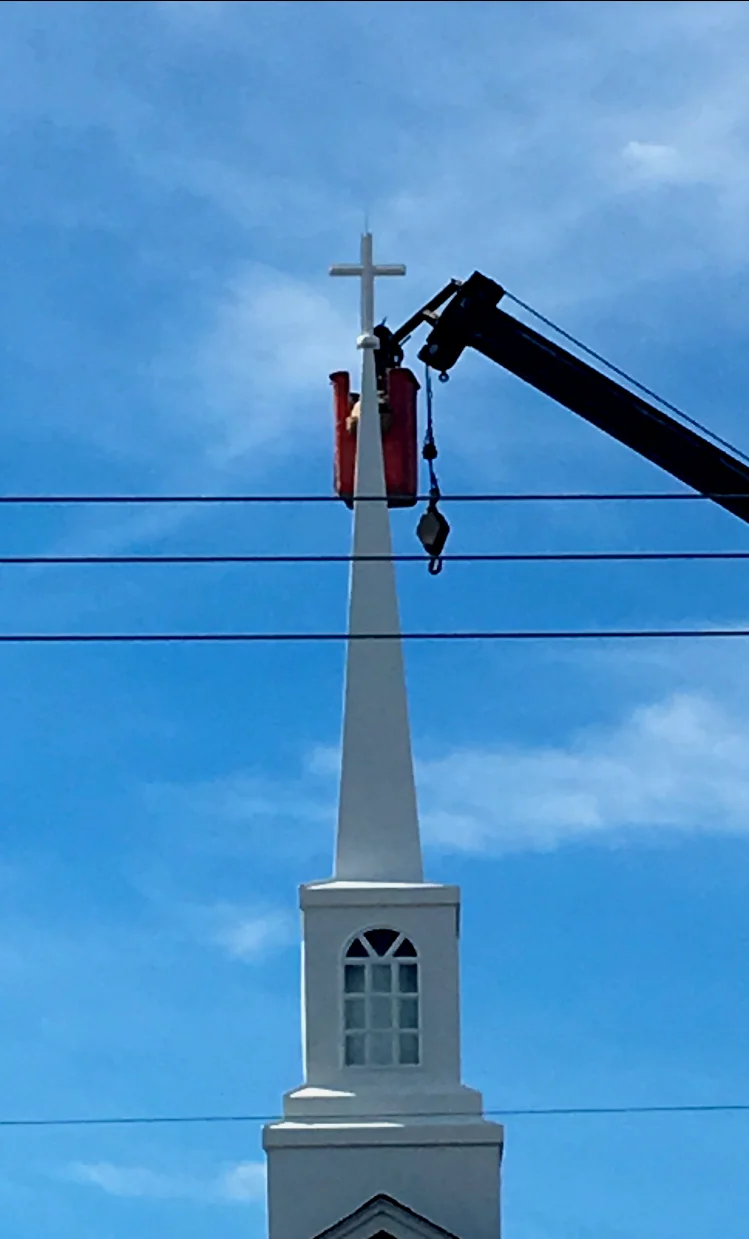 A worker securing the cross atop the new church steeple.