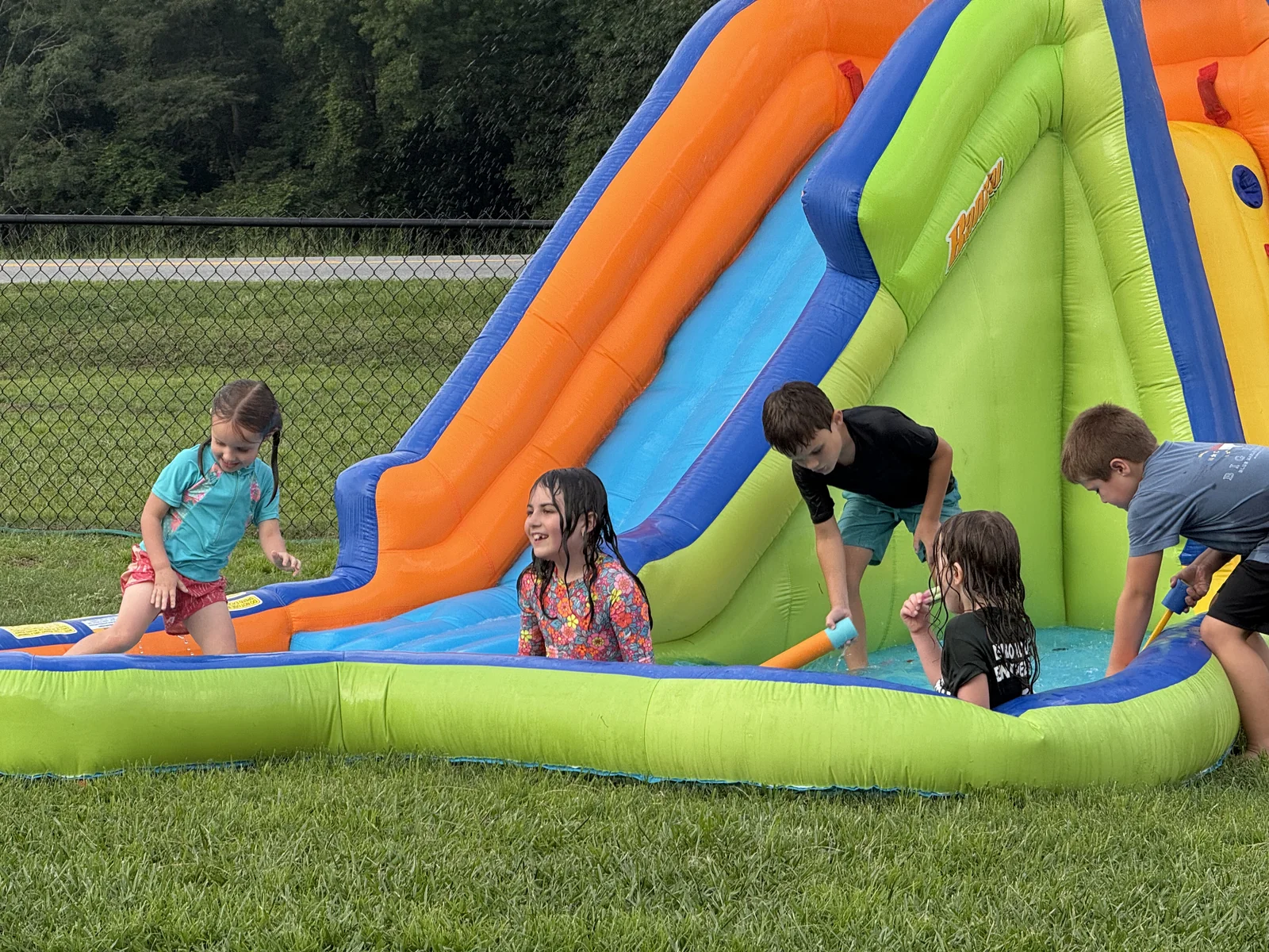 Children playing on a water slide during Backyard Bible Club.