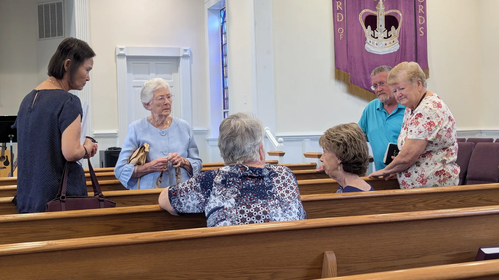 Members of Rawls Baptist Church talking together in the sanctuary pews.