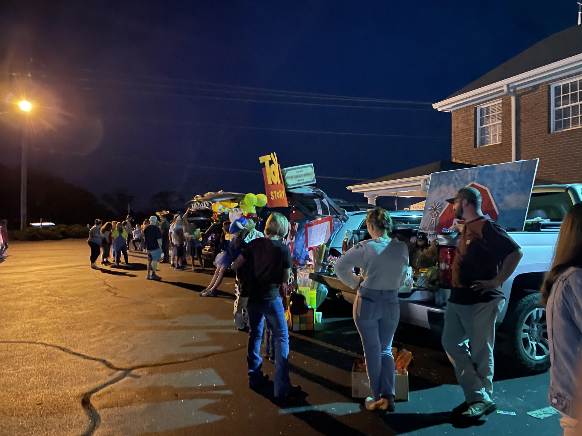 Families and decorated vehicles filling the Rawls Baptist Church parking lot during Trunk or Treat.