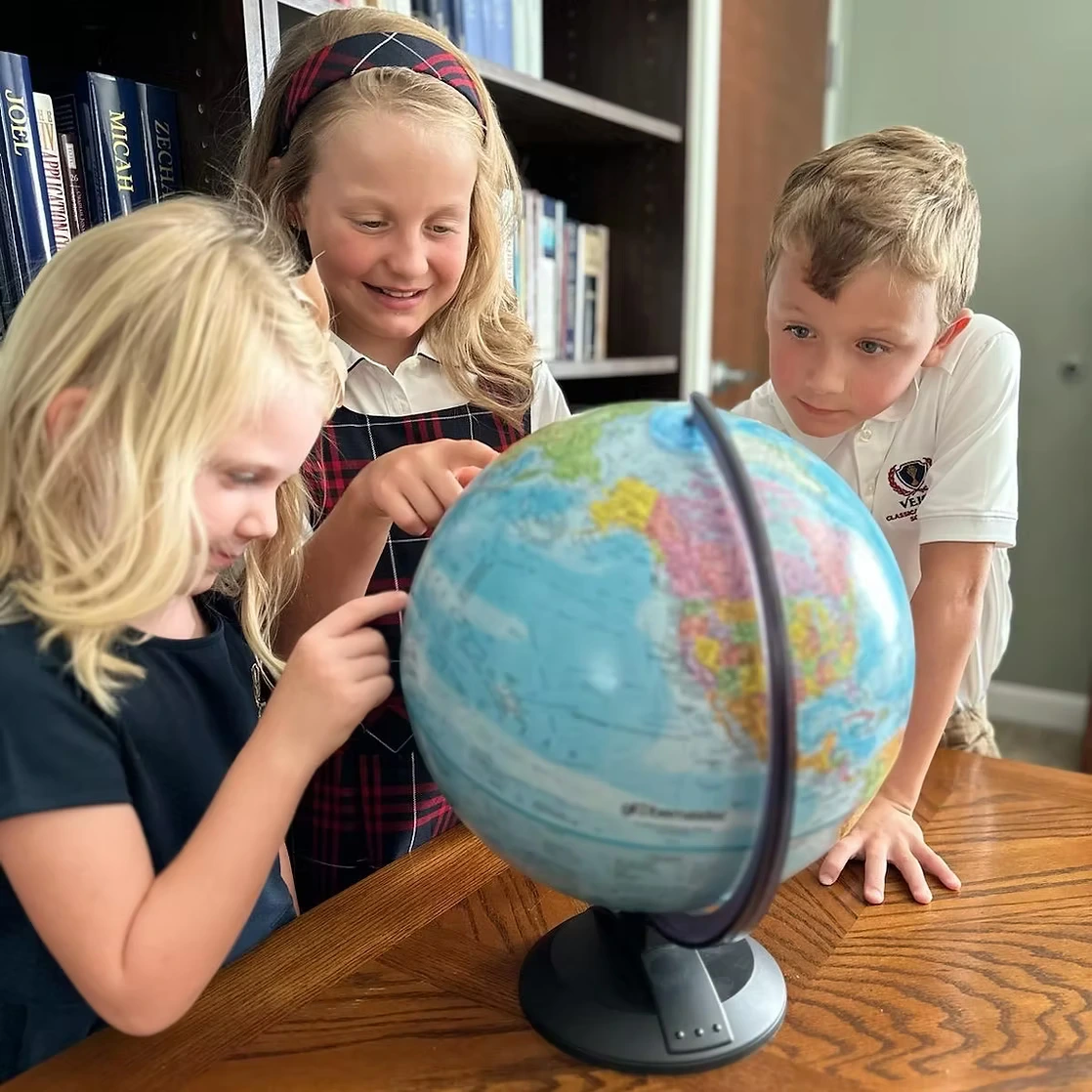 Velos students studying together around a globe.