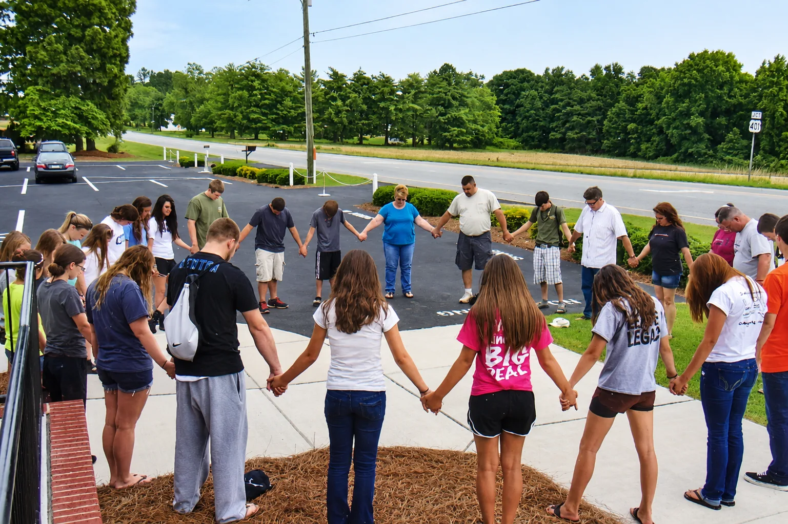Members of Rawls Baptist Church gathered in a prayer circle outdoors.
